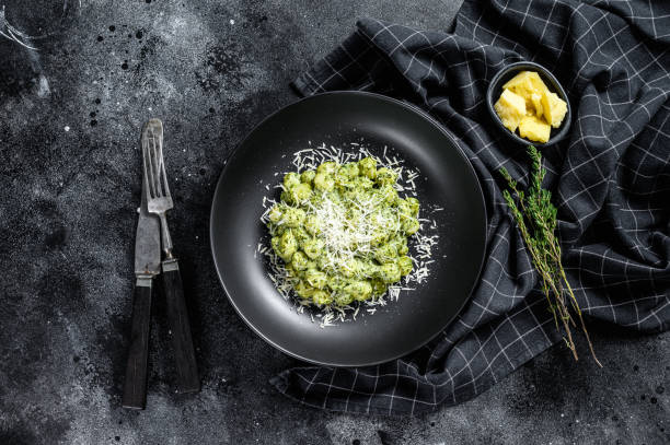 Gnocchi with basil spinach sauce and Parmesan. Italian potato paste. Black background. Top view