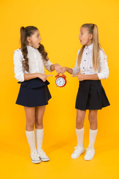 Schoolgirls and alarm clock. Children school pupils. Knowledge day. School time. Surprised shocked kids hold alarm clock counting time. Latecomer will be punished. It is time. School schedule. colegialas y despertador. alumnos de la escuela infantil. día del conocimiento. hora de la escuela. sorprendidos niños sorprendidos mantener el tiempo de conteo del reloj despertador. el recién llegado será castigado. ya es hora. horario escolar