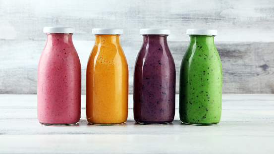 Assortment of fruit smoothies in glass bottles. Fresh organic Smoothie ingredients. Smoothies for health or detox diet food concept.