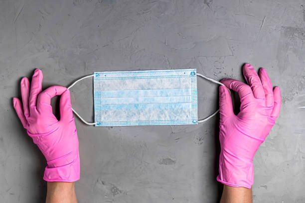 istock Women's hands hold medical mask on grey background. 1222004536