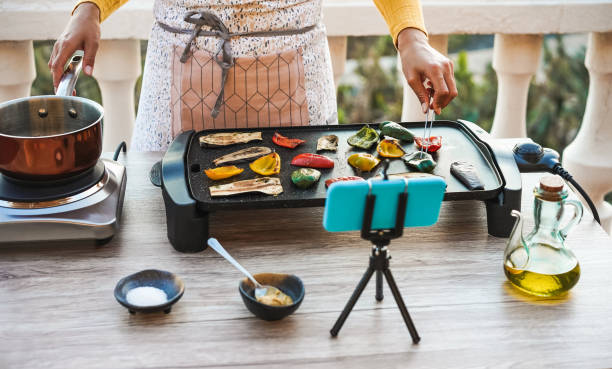 istock Young woman chef cooking outdoor while streaming online for webinar masterclass lesson at home during isolation quarantine - Food concept - Main focus on vegetables 1222004666