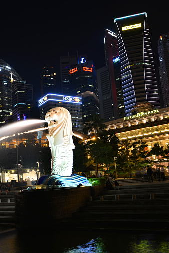 Marina Bay skyline with the uplit city icon, the Merlion and the Fullerton Hotel in the foreground at night in Singapore