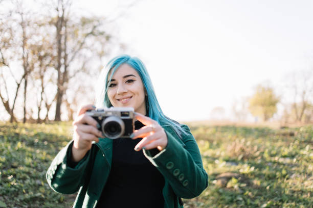 istock Girl looking into a camera while holding photo camera 1222007139