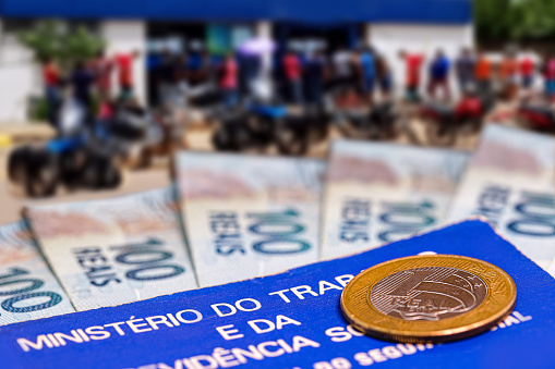billetes de 100 sedes de Brasil, en una tarjeta de trabajo, con una línea borrosa de personas en el fondo. Personas desempleadas, aglomeración. Concepto de beneficios sociales de Brasil. photo