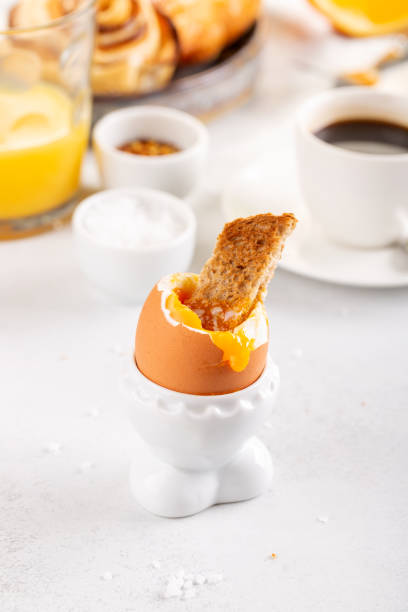Delicious breakfast with soft boiled eggs, toasted bread, cup of coffee and orange juice.
