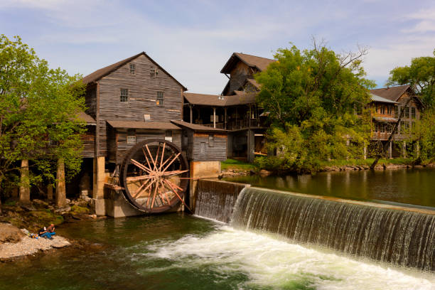 Pigeon Forge, Tennessee, USA - April 22, 2020: Two men fish next to the Old Grist Mill, built-in 1830 on the banks of the Little Pigeon River during the pandemic.