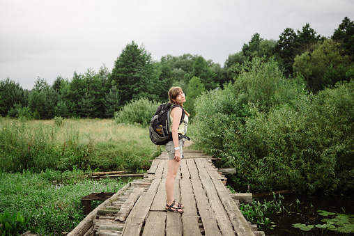 Shot of female hiker standing on the pathway across the swamp