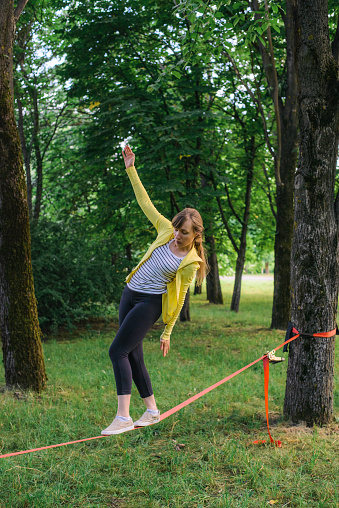 Young woman slacklining in summer park