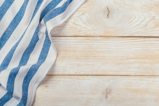 istock Top view on a white wooden table with a linen kitchen towel or textile napkin. a tablecloth on a light wood countertop. Copy space for text. 1222015343