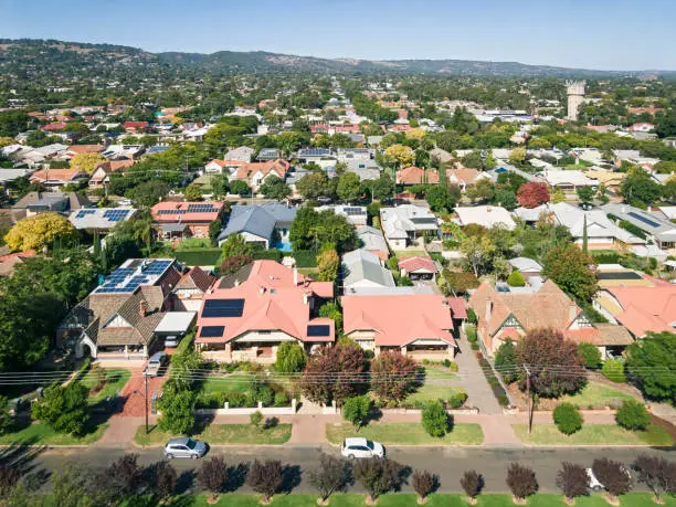 Elevated view of houses & rooftops in leafy eastern suburb of Adelaide during the transition from summer to autumn: sunny with autumn leaf colours. Note the many solar panels installed on the rooftops providing power generation for the city.