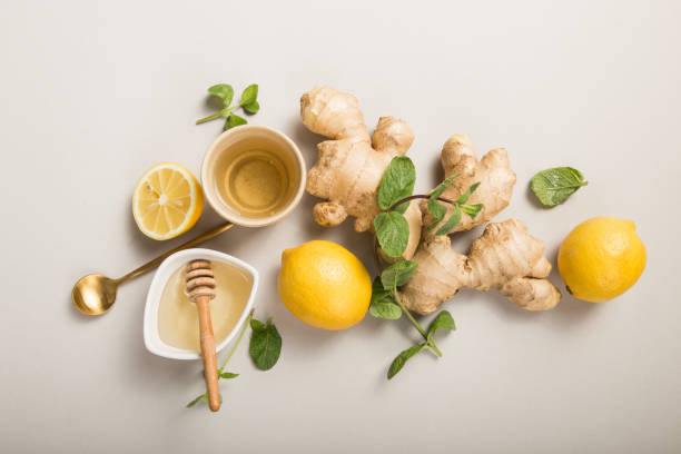istock Ginger Lemon Tea with Honey. Warming immune boosting tea with citrus and ginger. Cup, honey,  ginger root on grey  pastel background, copy space, top view. 1222016941