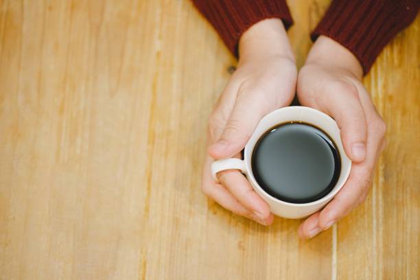 istock image of hands holding cups of coffee on rustic wooden table. 1222018234