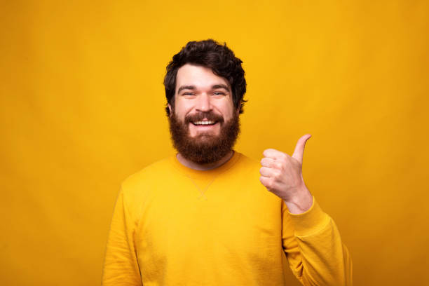 istock Handsome bearded man is showing like or thumb up on yellow background. 1222021572