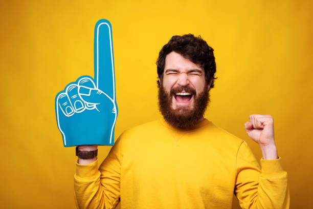 istock Excited young man is wearing a foam fan glove while making winner gesture. 1222021815