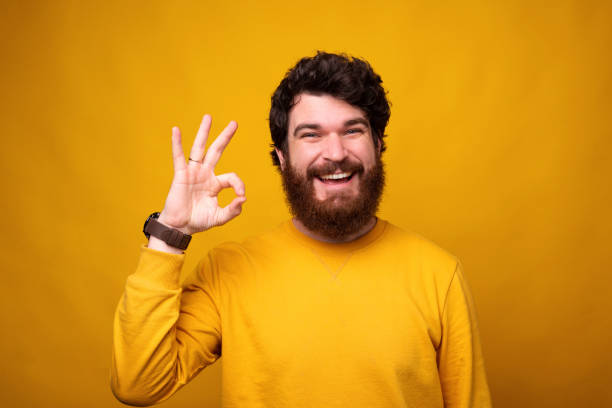 istock Smiling man is showing ok gesture on yellow background. 1222022139