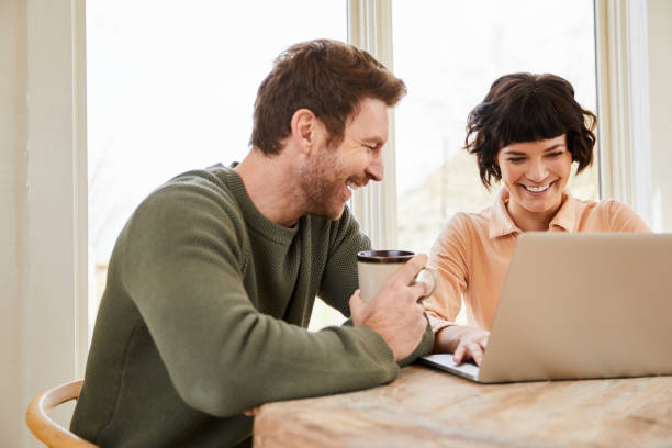 istock Laughing couple sitting together while using a laptop at home 1222022501