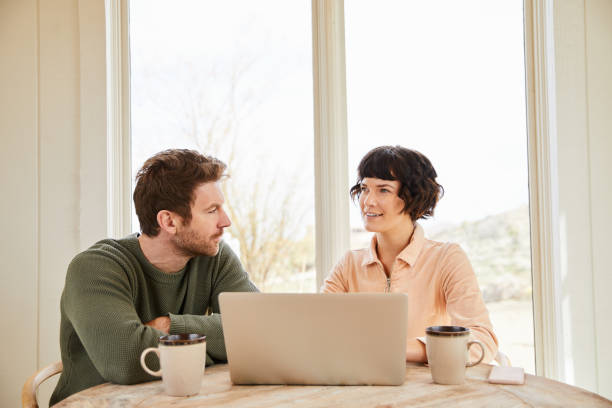 istock Couple talking and using a laptop at their table at home 1222023085