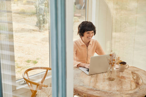 istock Laughing young woman sitting at home using a laptop 1222024595