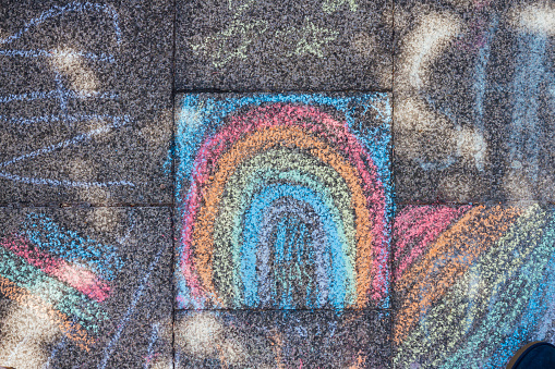 A colorful chalk drawing of a rainbow drawn on a footpath.