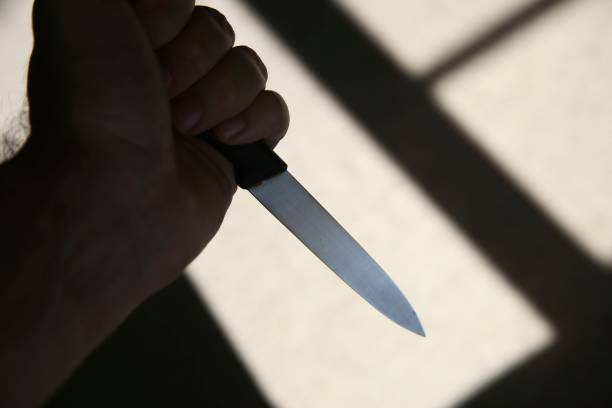 A hand holding a knife in shadow. This image can be used to represent stabbing or murder. A hand holding a knife in shadow. This image can be used to represent stabbing or murder. knife crime photos stock pictures, royalty-free photos & images