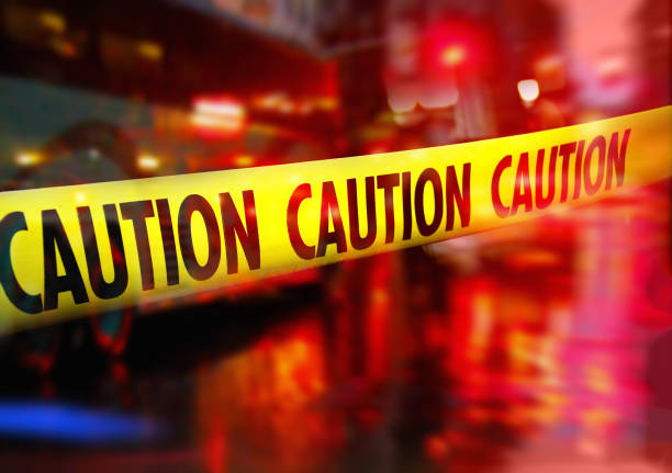 istock Crime scene caution tape and blurred law enforcement  background 1222029799