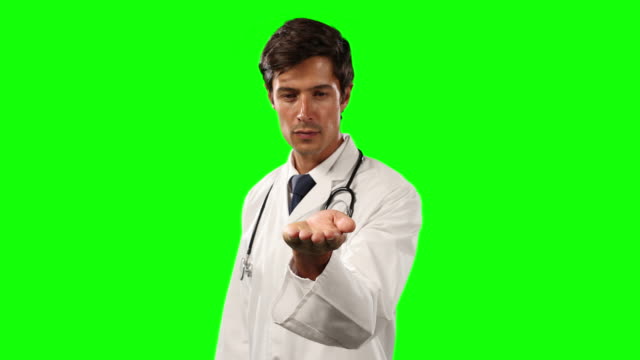 Front view of a doctor holding his hand for a copy space with green screen