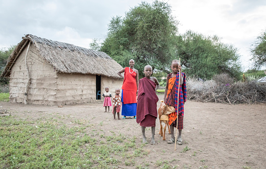 Group of Maasai, men and women standing outside their hut in village close to Serengeti Tanzania.