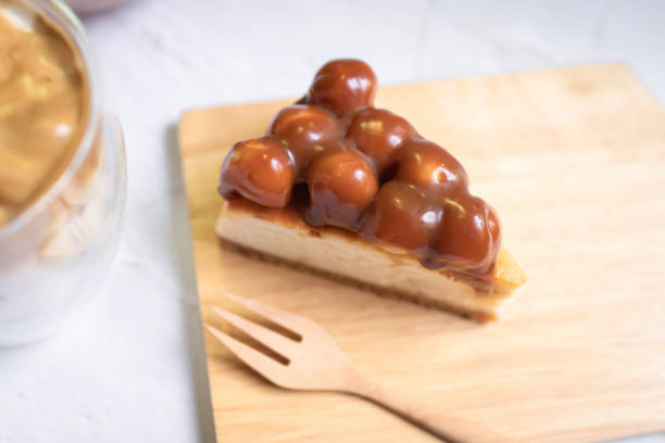 istock Caramel macadamia cheesecake with wooden fork on wooden tray. 1222033213