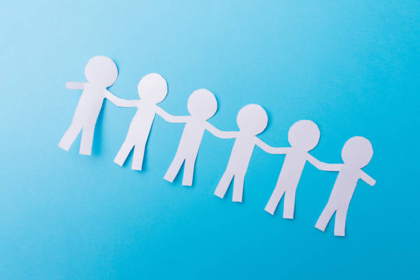 istock White paper people holding hands. Blue background 1222033975