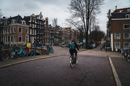 A young woman cycling on the bridge in Amsterdam, Netherlands. Horizontal composition.