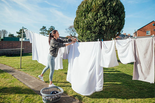 Female nursing student doing her washing hanging it up and collecting it in her garden.