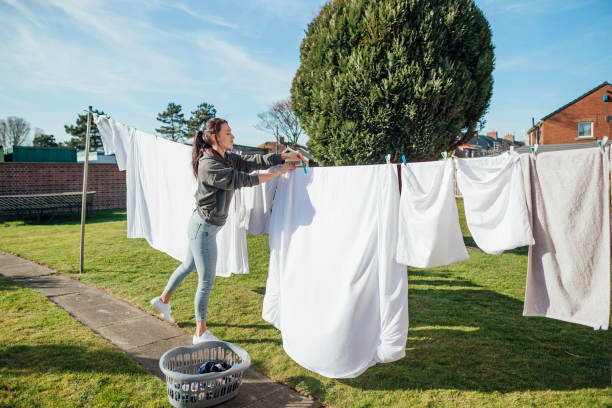 Working on Household Chores Female nursing student doing her washing hanging it up and collecting it in her garden. bed sheets stock pictures, royalty-free photos & images