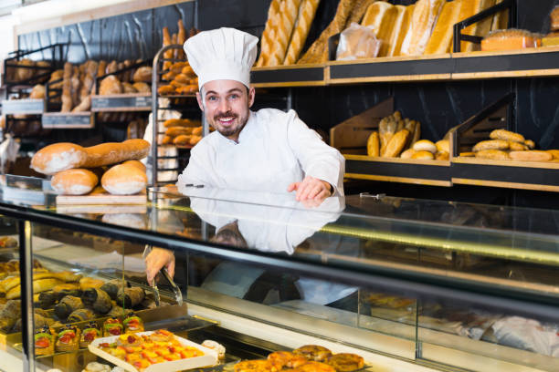 istock Man seller showing warm festive cake in bakery 1222036573