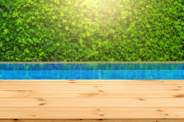 istock Wooden table in front with empty space for advertise display and blurred background of swimming pool and green garden 1222040519