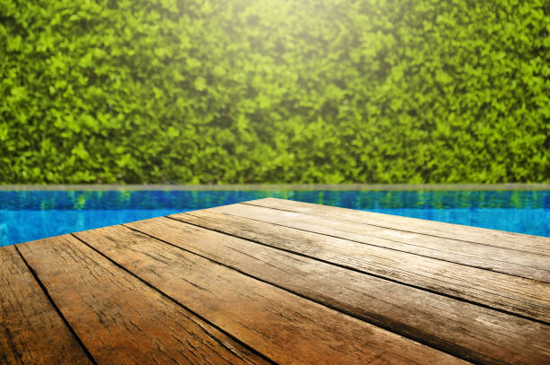 istock Wooden table in front with empty space for advertise display and blurred background of swimming pool and green garden 1222040817