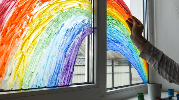 istock hand painting rainbow on a window, stay home during quarantine 1222042514
