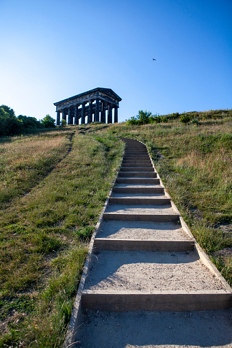 Path leading to The Penshaw Monument at the top of the hill set against a bright blue sky