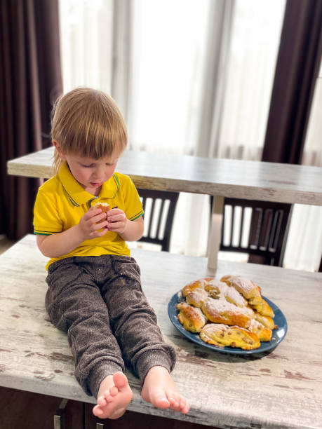 istock Little fair-skinned child eating freshly baked buns sprinkled with powdered sugar. 1222043376