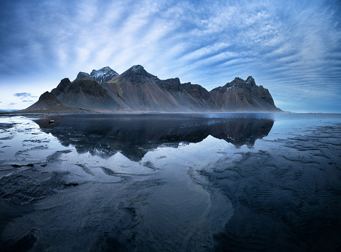 Vestrahorn mountains and Stokksnes beach near Hofn, southern Iceland. Mirror reflection and black vocanic sands at low tide.