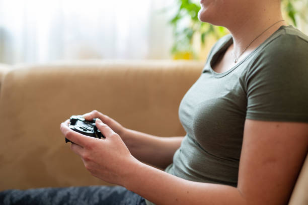 istock Smiling Caucasian young adult playing videogames with a controller in her hand on sofa 1222044135