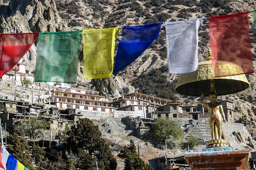 Brightly coloured Buddhist prayer flags fluttering in the thin mountain air beside traditional white washed stupas below the Sherpa village of Namche Bazaar, high in the Sagarmatha National Park, Himalayas, Nepal.