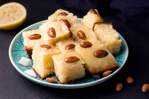 istock arabic sweet Basbus pie cut into slices on a black background next to a lemon and blue textile 1222050675