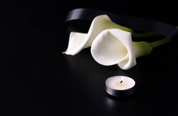 istock fresh calla flower next to candles on a black background. copy space. banner 1222052243