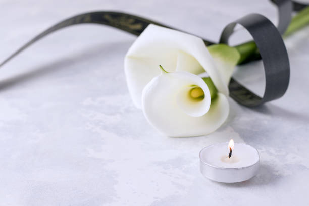 istock White flowers with a mourning ribbon on a concrete background. Copy space. Death concept 1222052287