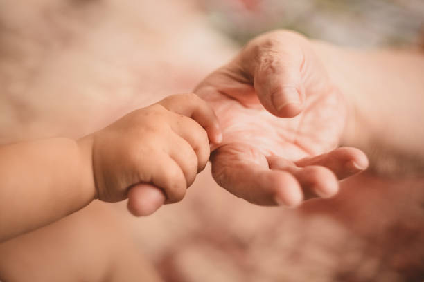istock The child's small hand encircles the old woman's finger 1222052370