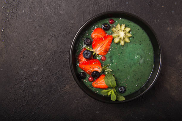 Colorful, healthy food. Acai smoothie bowl. Keto breakfast idea. Fruit curd smoothie, acai. Breakfast with green spirulina, strawberry, chia, kiwi in black plate stock photo