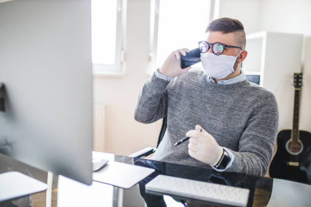 istock Businessman using phone and wearing protective face-mask and surgical glove 1222061209