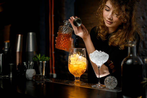 istock female bartender pours drink from jigger into mixing cup with ice. 1222064847