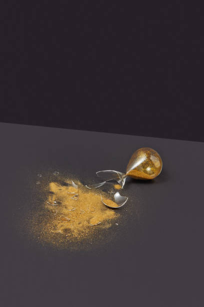 istock Crashed outdated hourglass with golden sand on a black duotone background. 1222064861