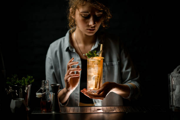 istock young woman bartender holds glass with ready-made fresh cold cocktail. 1222068201